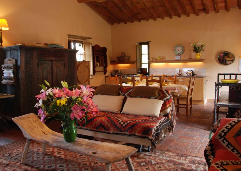 Der Wohn-Essbereich der Villa Compignano Barn in der Toskana mit Küchenzeile, Esstisch, gemütlicher Couch und Sesseln